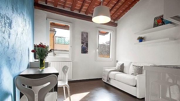 A modern kitchen with a dining area, white furniture, and a view of the outside. - San Gallo Suites V (Florence)