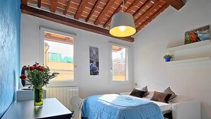 A bedroom with a bed, a desk, a chair, a window, and a ceiling fan. - San Gallo Suites V (Florence)