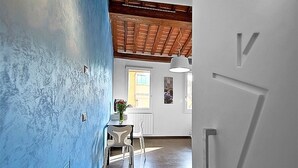 A hallway with a blue wall, a wooden ceiling, and a white door. - San Gallo Suites V (Florence)
