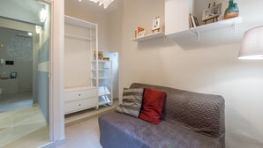A compact living space with a grey sofa, a white wardrobe, and a small shelf with decorative items. - San Lorenzo Chic (Florence)