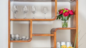 A wooden sideboard with multiple shelves, some holding glassware and a vase with flowers. - San Lorenzo Terrace (Florence)