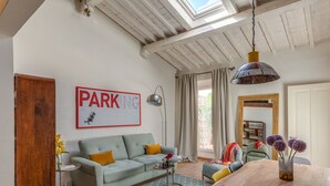 A living room with a sofa, a coffee table, a dining table, and a large window with curtains. - San Lorenzo Terrace (Florence)