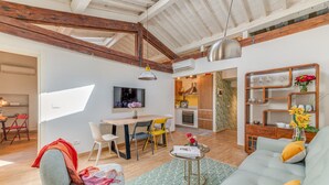 A spacious living area with a sofa, a dining table with chairs, a TV, and a kitchen in the background. - San Lorenzo Terrace (Florence)