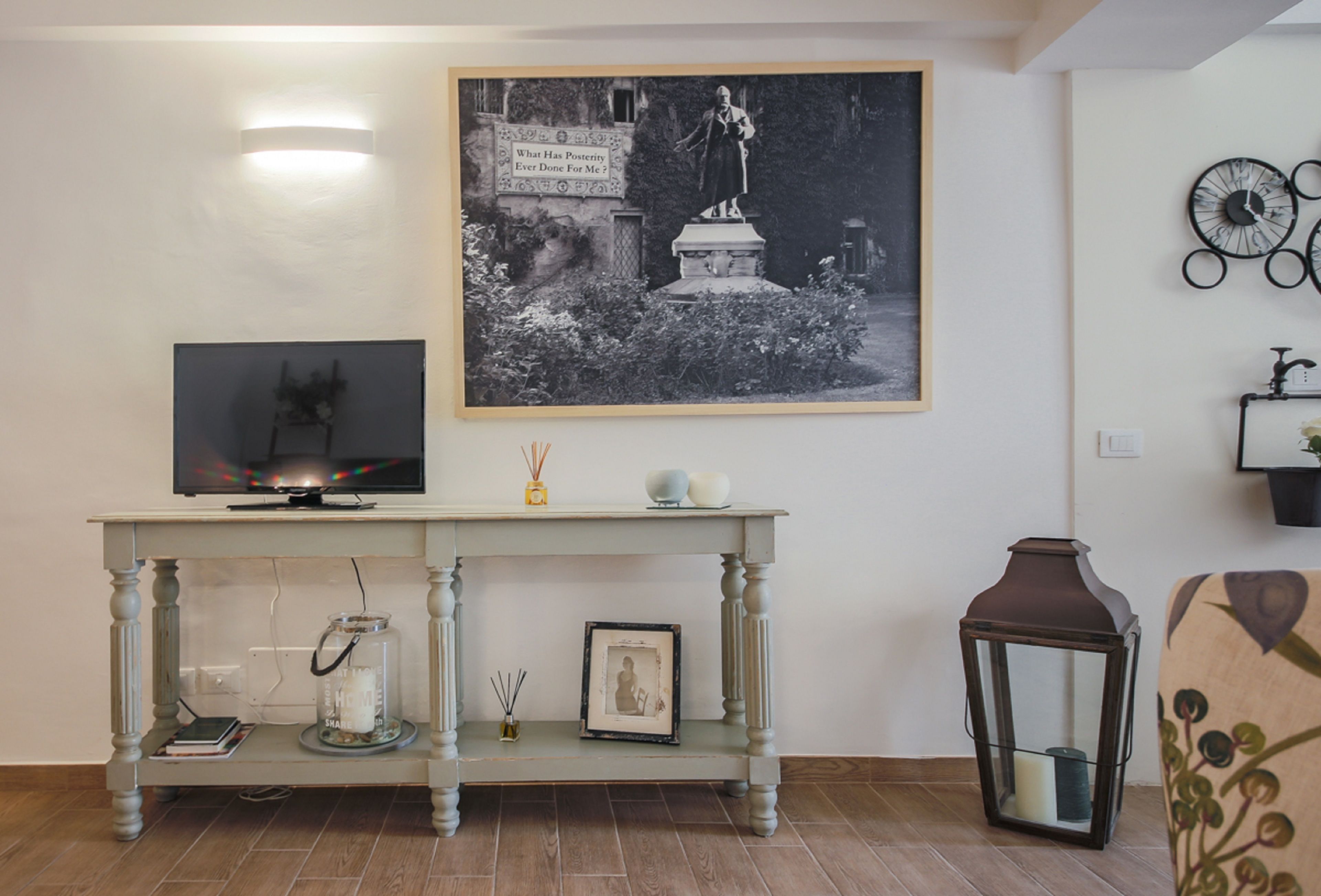 A living room with a television on a table, a framed picture, a statue, and a wall clock.
