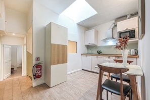 Une cuisine moderne dotĂ©e dâune verriĂšre, de meubles blancs, dâun four Ă micro-ondes et dâun coin repas avec une table et des chaises.