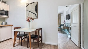 A dining area with a table, chairs, a vase with flowers, a microwave, and a cabinet. - San Marco Suite VII (Florence)