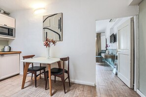 A dining area with a table, chairs, a vase with flowers, a microwave, and a cabinet.
