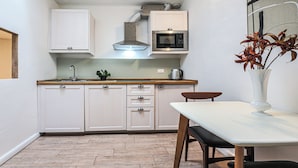 A compact kitchen with white cabinets, a microwave, and a small dining table with chairs. - San Marco Suite VII (Florence)