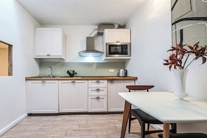 A compact kitchen with white cabinets, a microwave, and a small dining table with chairs.