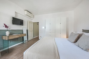 A bedroom with a bed, bedside table, TV, wardrobe, and an air conditioning unit.
