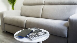 A grey sofa with a white table in front, holding a magazine and a smartphone. - Sant’Ambrogio Passion (Florence)