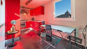 Een moderne keuken met rode kastjes, een eetgedeelte met metalen stoelen, en een uitzicht op een koepel door een raam.