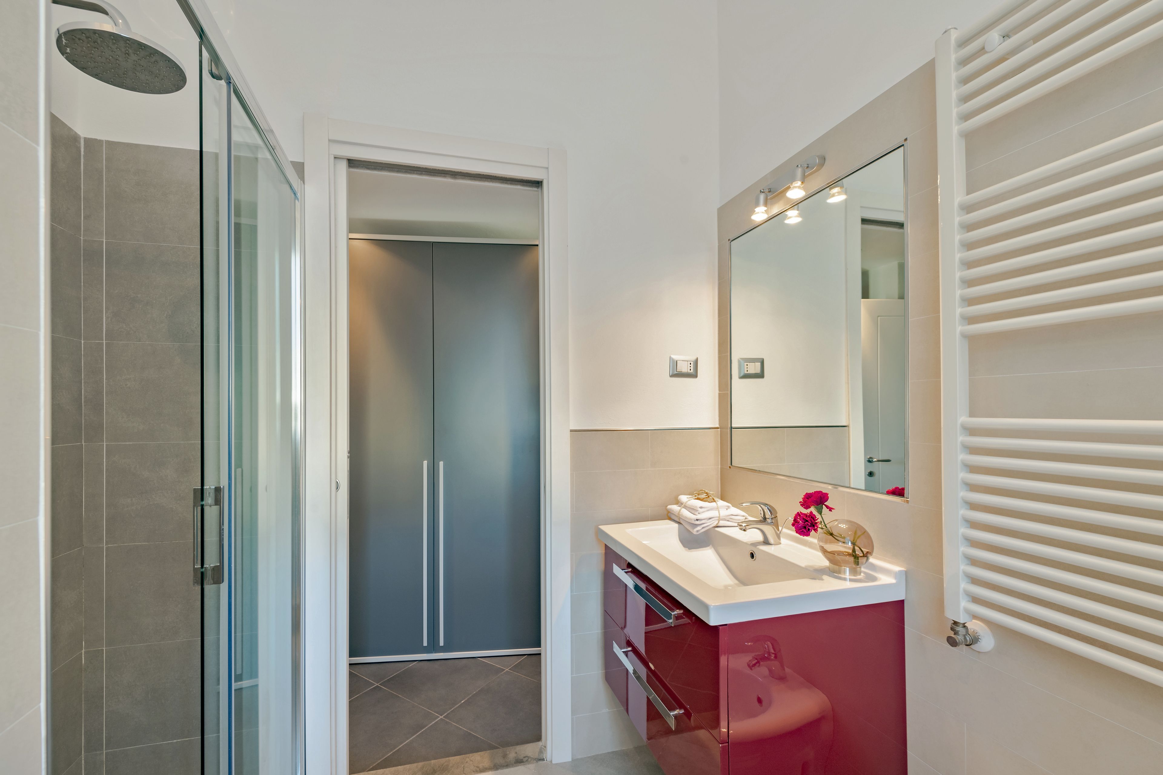 A modern bathroom with a glass shower enclosure, a vanity with a mirror, and a towel rack.