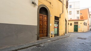 Una estrecha calle adoquinada con una puerta de madera y una puerta verde en un edificio amarillo.