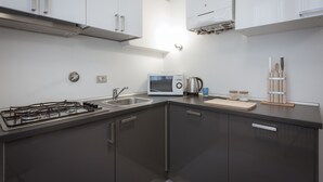 A modern kitchen with a gas stove, microwave, sink, and cabinets. - Stylish Anguillara (Florence)