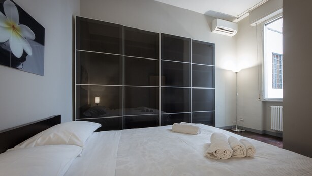 A modern hotel room with a large bed, a wardrobe, and a window with a view. - Stylish Anguillara (Florence)