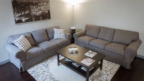 A living room with two grey sofas, a coffee table, a floor lamp, and a framed cityscape picture on the wall. - Stylish Anguillara (Florence)