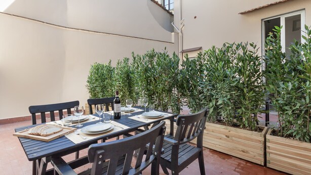 Een eetruimte met een tafel voor vier personen, omringd door houten stoelen en een houten bank.
