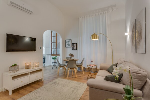 Un salon moderne doté d’un téléviseur à écran plat, d’un canapé, d’un coin repas avec des chaises et d’une table basse.
