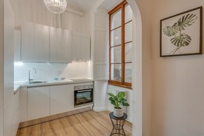 A modern kitchen with white cabinetry, a built-in oven, and a window with a wooden frame. - Terme Chic (Florence)