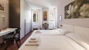 Een hotelkamer met twee bedden, een bureau, een stoel en een schilderij aan de muur.