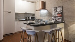 Een moderne keuken met witte kasten, een centraal eiland met barkrukken, een magnetron en een koffiezetapparaat.