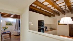 Una cocina moderna con vigas de madera, horno empotrado y una lámpara colgante.