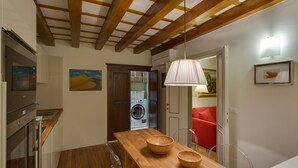 Una cocina moderna con vigas de madera, encimera de madera y una lámpara colgante.