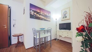 Un comedor con una mesa, sillas, un televisor y un cuadro en la pared.