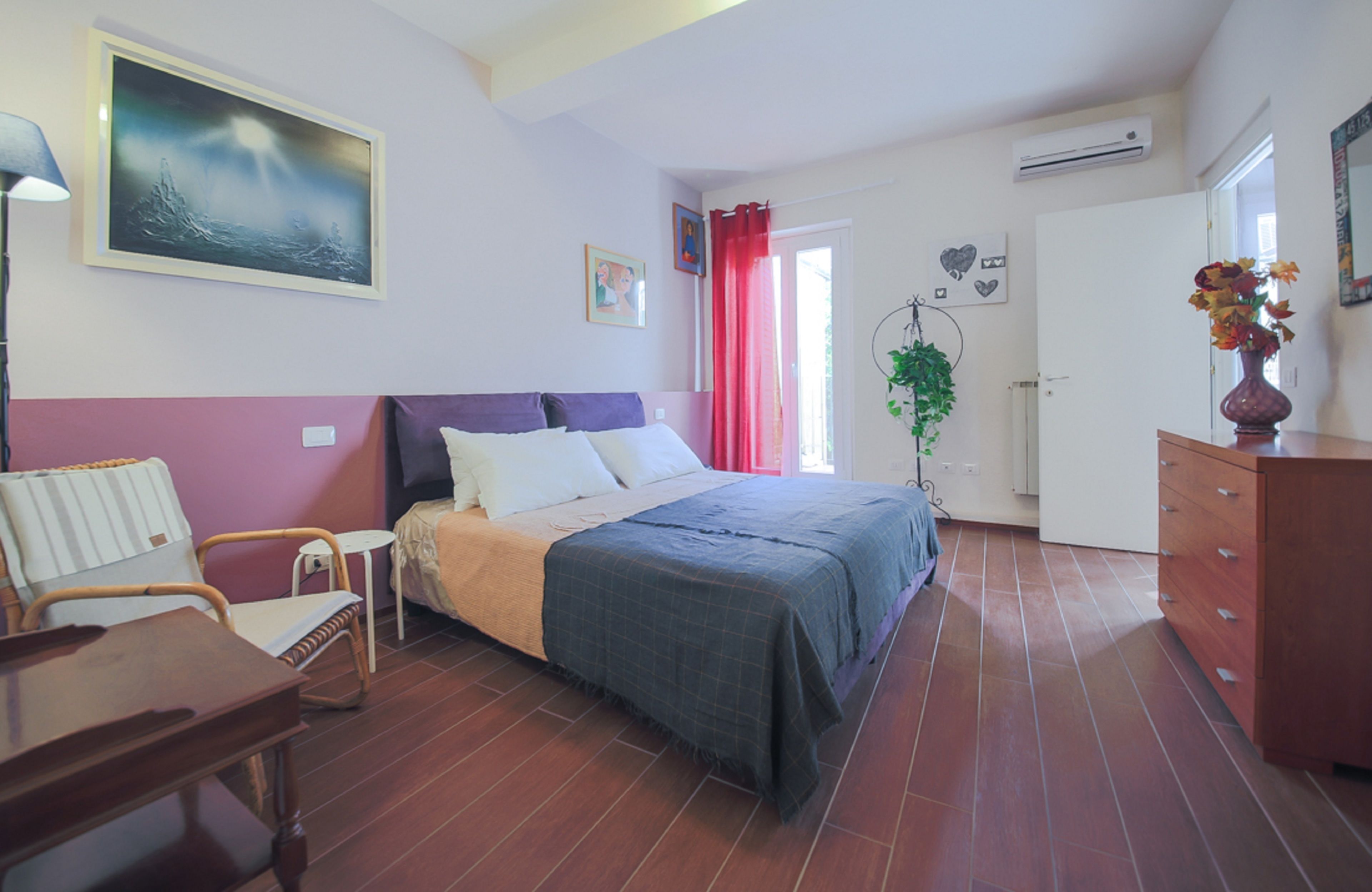A bedroom with a bed, a chair, a dresser, and a painting on the wall.