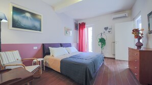 Un dormitorio con cama, una silla, un aparador y un cuadro en la pared.