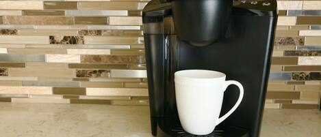 A Keurig coffee maker with a white mug and two coffee pods on a countertop.