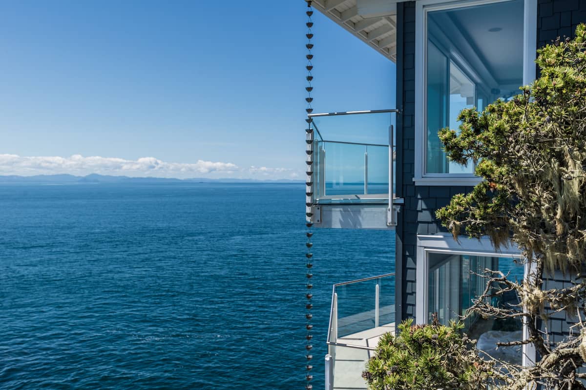 A modern building with a glass balcony overlooking a large body of water.