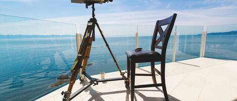 Un telescopi sobre un trípode, una cadira i una vista del mar.