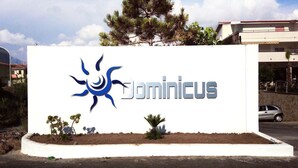 A sign with the word "Dominicus" and a sun-like logo. - Suite Hotel Club Dominicus (Grisolia)