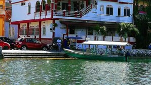 A multi-story building with balconies and a flag, situated by a body of water. - Hotel La Union (Flores)