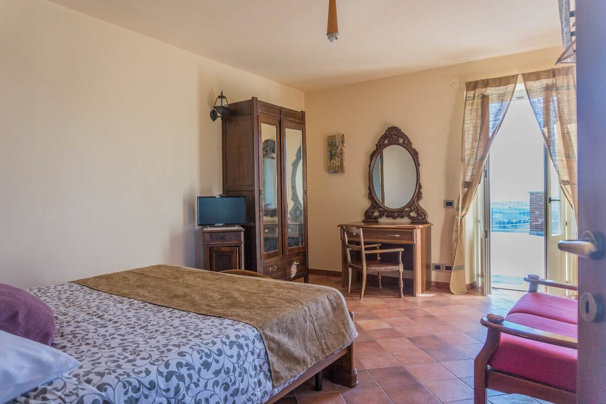 Un dormitorio con una cama, un escritorio de madera, una silla, un armario y un espejo grande.