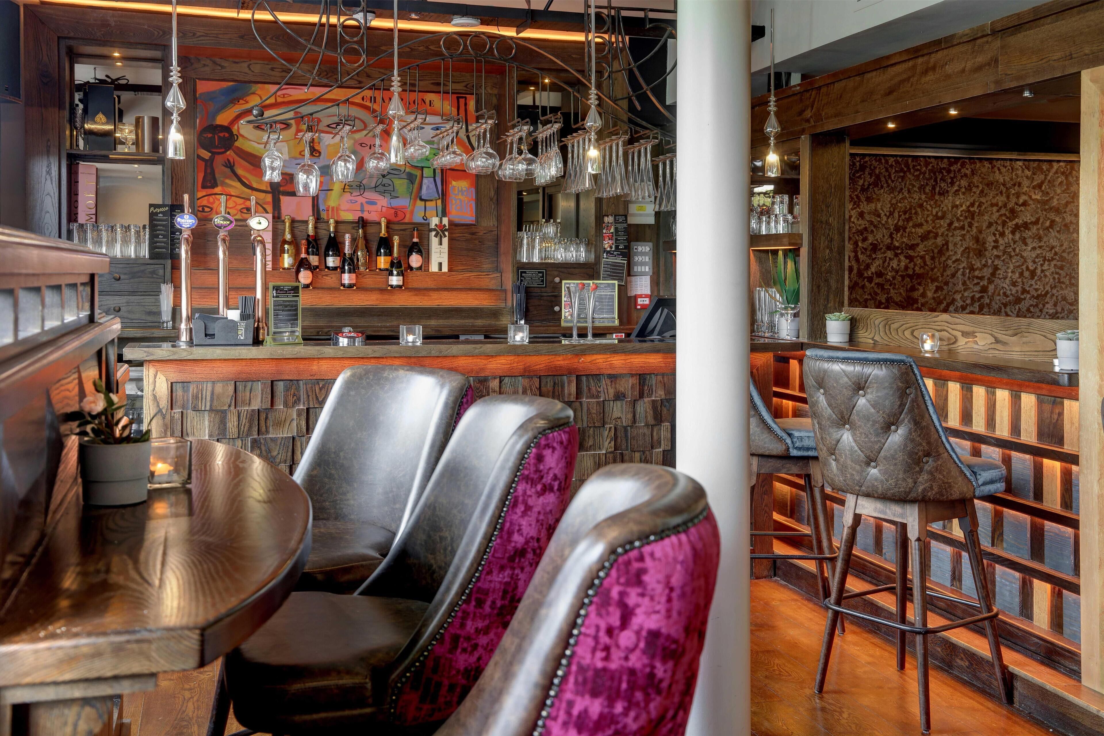 A bar area with multiple seating options, a bar counter with taps, and a decorative wall.