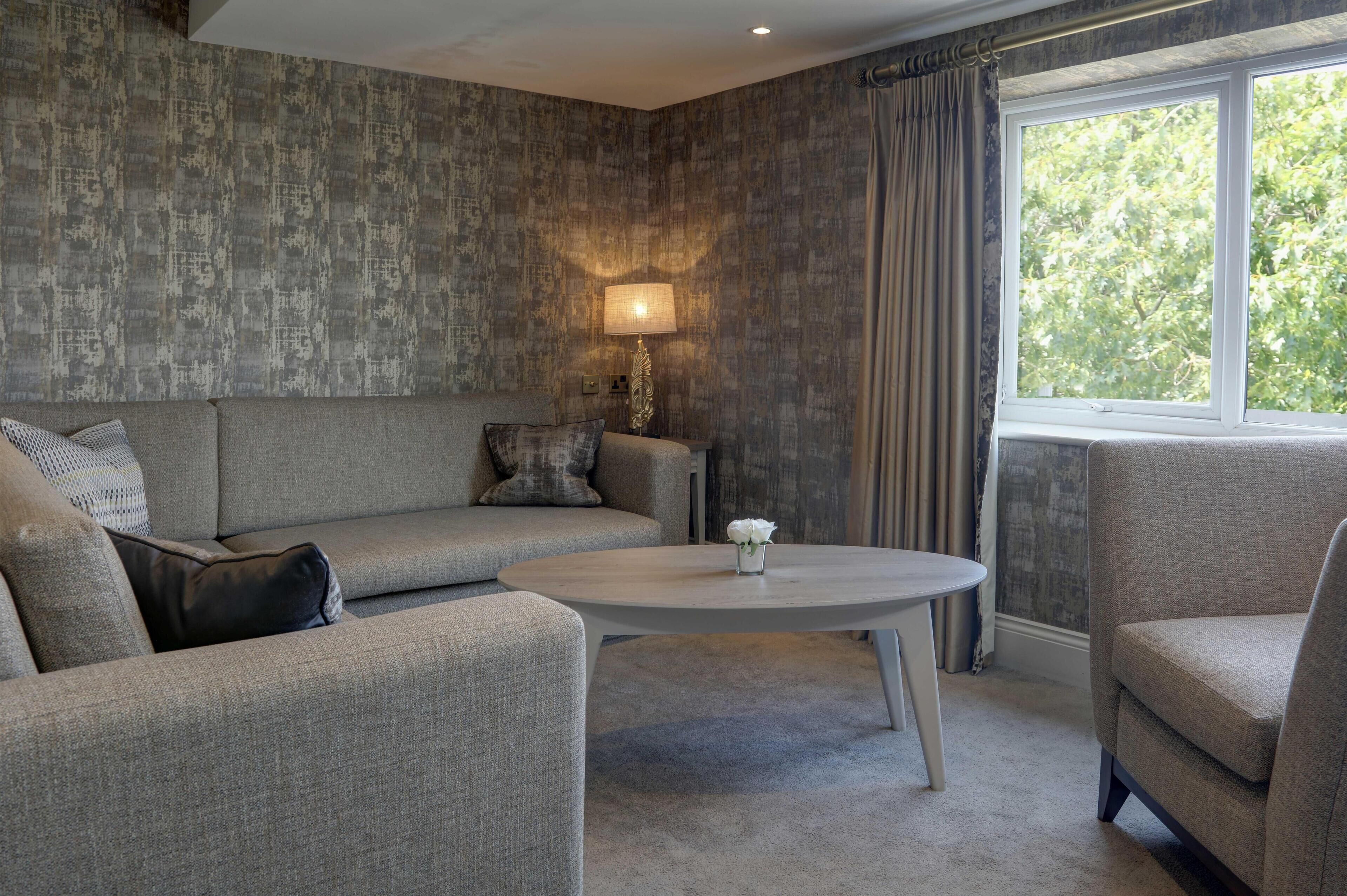 A modern living room with a grey sofa, a round coffee table, and a lamp.