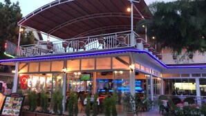 A restaurant with outdoor seating, a covered patio, and a bar area. - Sun Kiss Otel (Manavgat)