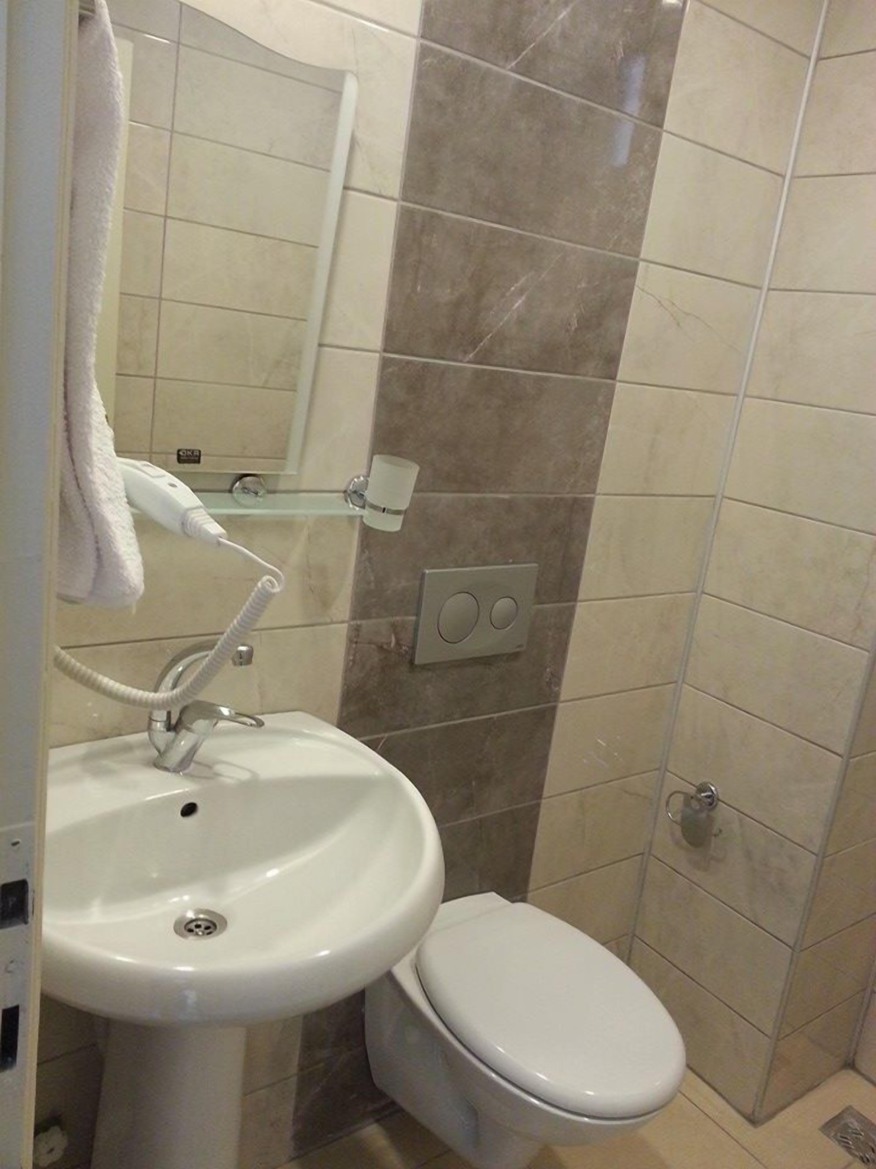 Casa de banho com lavatório branco, sanita e zona de duche.