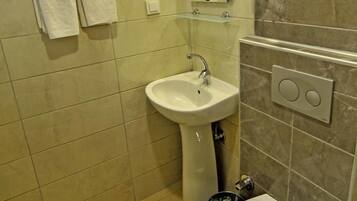 A bathroom with a sink, toilet, and hand dryer.