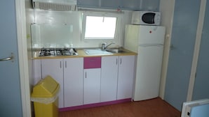 A compact kitchen with a gas stove, microwave, and refrigerator. - Camping le Lanfonnet (Talloires-Montmin)