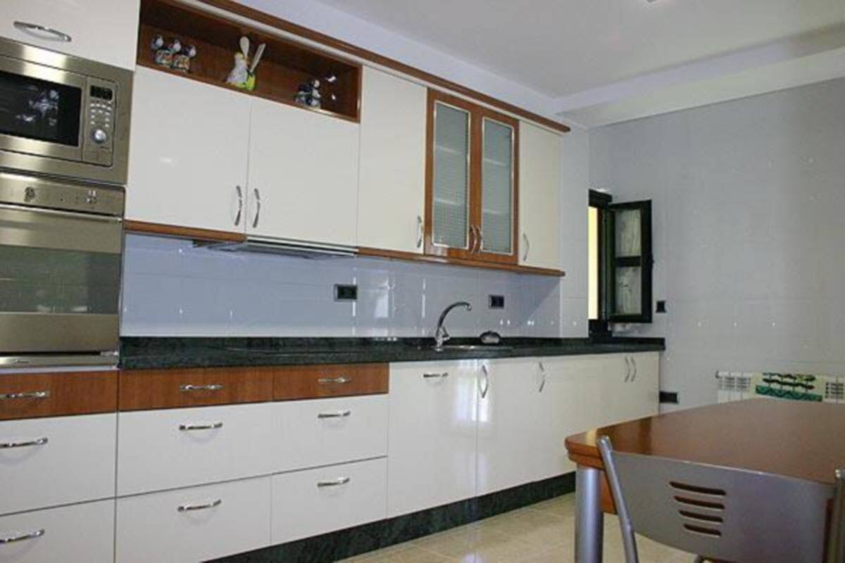 A kitchen with white cabinets, a wooden countertop, and a stainless steel oven.
