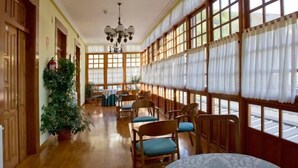 Un largo pasillo con puertas de madera, una planta en maceta y un candelabro.