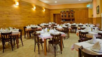 A dining area with multiple tables set for service, wooden walls, and a tiled floor.