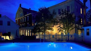Una casa grande con piscina, un patio cercado y una entrada bien iluminada.
