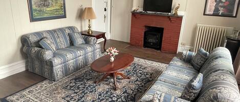 A living room with a sofa set, a coffee table, a fireplace, and a television.