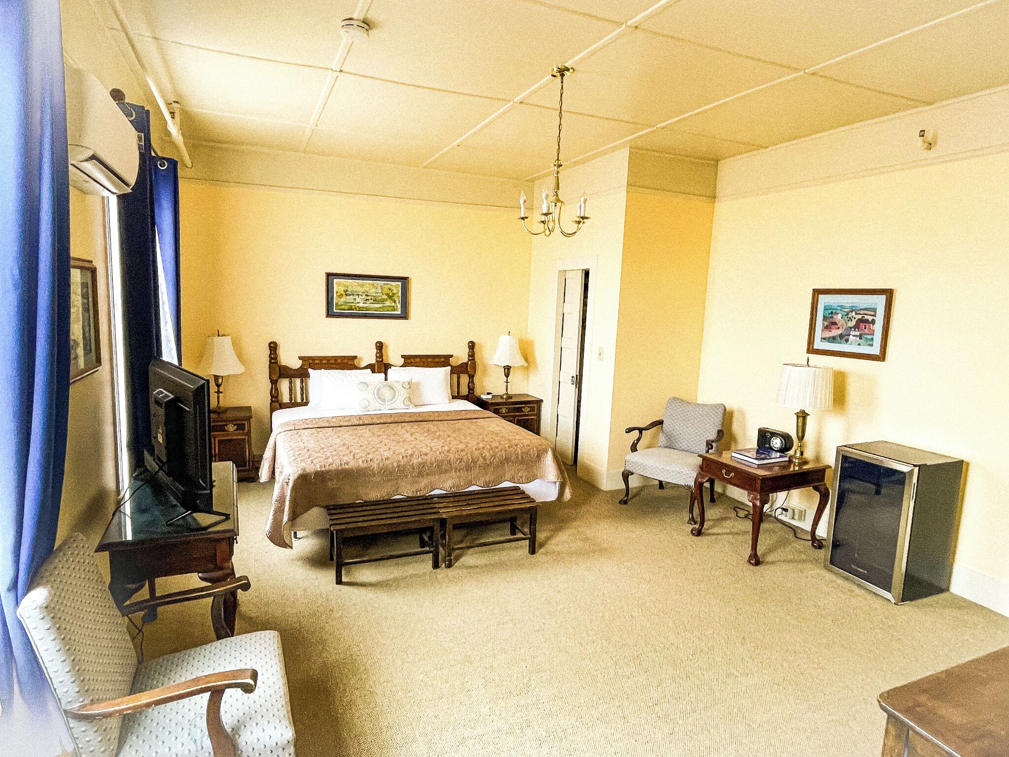 Une chambre d’hôtel équipée d’un lit, de tables de chevet, d’une chaise, d’un téléviseur et d’un bureau avec un ordinateur.
