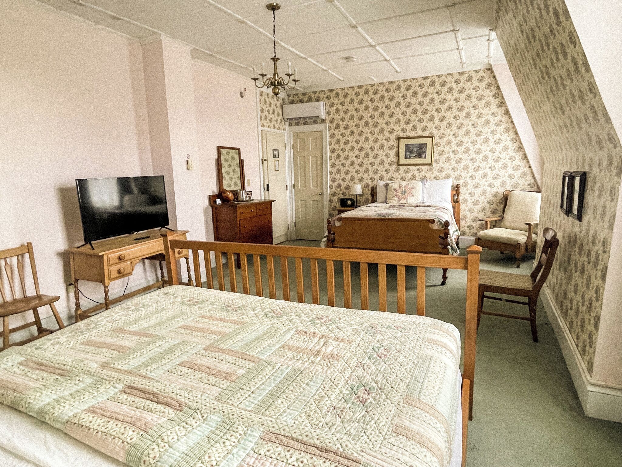 A bedroom with a bed, a television, a dresser, a chair, and a desk.